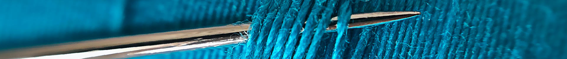Close-up of needle through blue threads