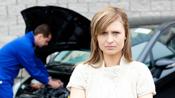 Upset woman standing in front of a broken down car